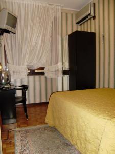 a bedroom with a bed and a television and a window at Hotel Italia City Center in Mantova