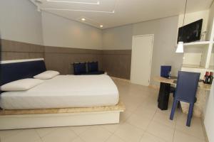 a bedroom with a bed and a desk and a television at Raru's Motel Litoral Norte (Adult Only) in Natal