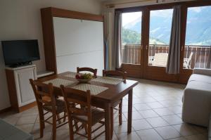 ein Wohnzimmer mit einem Tisch, Stühlen und einem TV in der Unterkunft Monolocale Casericc in Piatta
