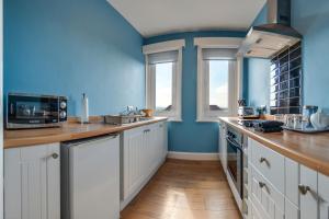 a kitchen with white cabinets and blue walls at The Whitby Prospect in Whitby