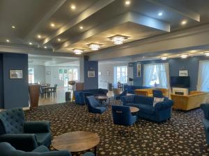 a lobby with blue couches and chairs and a table at Torbay Court Hotel in Paignton