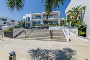 a large white building with stairs and palm trees at Tasia Maris Oasis in Ayia Napa