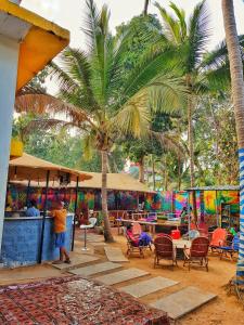 a man standing under a palm tree next to a restaurant at The Lost Hostel, Goa - Palolem Beach in Palolem