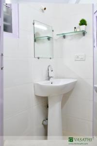 a white bathroom with a sink and a mirror at Vasathi in Madikeri
