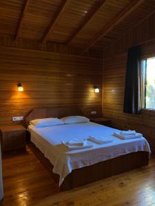 Un dormitorio con una cama grande en una habitación de madera. en Ozge Bungalow Hotel, en Cıralı