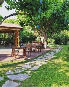 a picnic area with tables and chairs under a tree at Ozge Bungalow Hotel in Cıralı