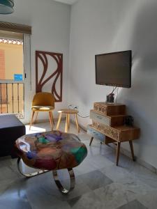 uma sala de estar com uma televisão de ecrã plano e uma cadeira em Centro Histórico con Balcón 2 Bedrooms em Málaga