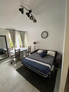 una camera con letto, scrivania e orologio di Magniolias - Résidence Calme avec Piscine, Tennis & Jardin a Antibes