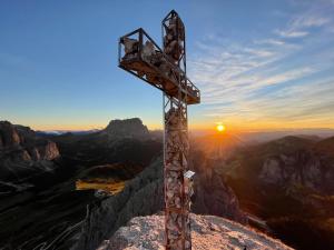 uma cruz no topo de uma montanha ao pôr-do-sol em Ostaria La Fontana em Corvara in Badia
