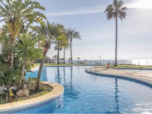 a swimming pool with palm trees and the ocean at MI CAPRICHO 3-5 BEACHFRONT- Apartment with sea views in Costa del Sol in Mijas Costa