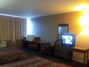 una habitación de hotel con TV en un tocador y una habitación en Indian Head Motel, en Winamac