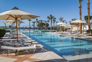 a pool at a resort with chairs and umbrellas at Jaz Fanara Resort in Sharm El Sheikh