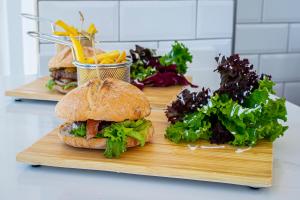 two sandwiches on a wooden cutting board with vegetables at Hotel Taimar in Costa Calma
