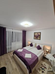 a bedroom with a large bed with purple sheets at Splendid House in Făgăraş