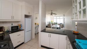 uma cozinha com armários brancos e um frigorífico branco em 72 Sea Lodge Umhlanga Rocks em Durban