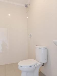 a white bathroom with a toilet and a shower at Karta House in Ubud