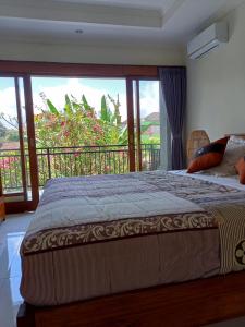 a bedroom with a bed and a large window at Karta House in Ubud