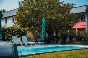 uma piscina com cadeiras e um guarda-sol e uma mesa e cadeiras em Vila Anna em Radenci