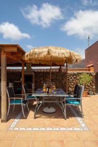 a table and chairs under an umbrella on a patio at Casa Mami in Lajares