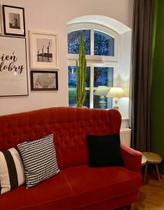 ein rotes Sofa im Wohnzimmer mit Fenster in der Unterkunft Kamienica 22 Old Town in Danzig