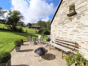 a stone building with a grill and a bench at Y Felin at Coed Cadw in Velindre-farchog