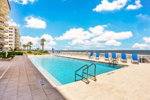 a swimming pool with chairs and the ocean in the background at Blue Umbrella in Daytona Beach Shores