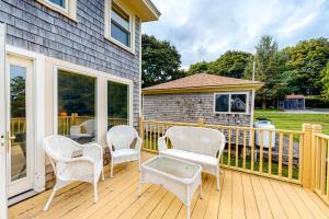 a wooden deck with chairs and a table on it at Lupine Cottage in Owls Head