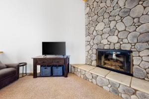 sala de estar con chimenea de piedra y TV en Bear Creek Escape, en Big Bear Lake