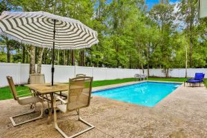 a table and chairs with an umbrella next to a pool at White House Home in St. Augustine