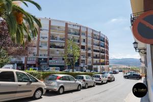 una línea de autos estacionados en una calle frente a un edificio en Apartment La Peineta Ronda, en Ronda