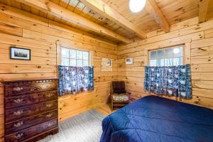 a log cabin bedroom with a bed and windows at Lake View Cottage in Leeds
