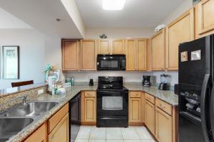 a kitchen with wooden cabinets and black appliances at Palms of Destin in Destin