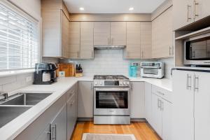 una cocina con armarios blancos y electrodomésticos de acero inoxidable en Ptown Treehouse en Provincetown
