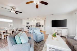 a living room with a couch and chairs and a tv at Blue Haven in Panama City Beach