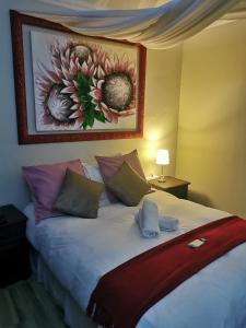 1 dormitorio con 1 cama con almohadas y una pintura en la pared en Harties Honeymoon Suite, en Hartbeespoort