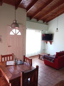 sala de estar con mesa de madera y sofá rojo en Casas Serranas Margaritas en Sierra de la Ventana