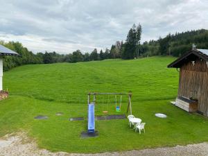 a playground in a field with a swing at Gasthof Rössle in Sulzberg