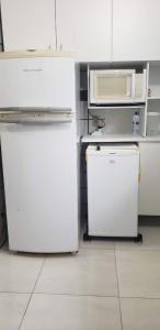 a kitchen with two refrigerators and a microwave at Apartamento San Martin in Caraguatatuba