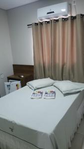 - un lit blanc dans une chambre avec rideau dans l'établissement Princesa do Vale Hotel, à Aparecida