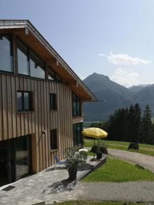 un edificio con sombrilla amarilla, mesa y silla en Inntalblick, en Nussdorf am Inn