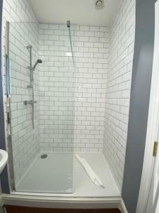 a bathroom with a shower and a white tile wall at The Great Western Hotel in Taunton
