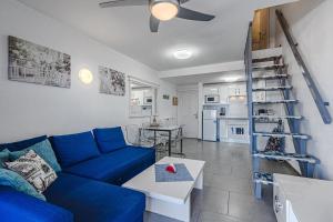 a living room with a blue couch and a kitchen at Las Américas Garden in Playa de las Americas