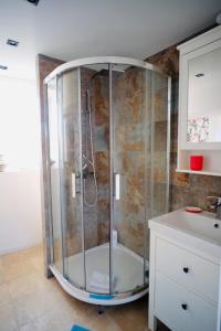 uma cabina de duche em vidro na casa de banho com um lavatório em le Perroquet Fringant em Caen