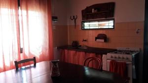 eine Küche mit einem Herd, einem Tisch und einem Fenster in der Unterkunft La Carmencita casa de campo, Manzanares, Pilar in Pilar