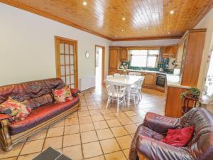 a living room with two leather couches and a kitchen at Clodagh's Cottage in Collooney