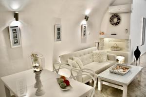 a living room with a white couch and a table at Aeolos Art & Eco Suites Adults Only in Imerovigli