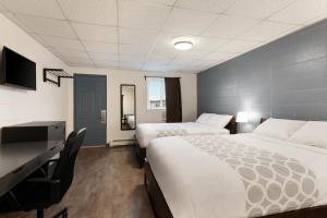 a hotel room with two beds and a desk at Howard Johnson by Wyndham Grande Prairie in Grande Prairie