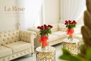 a living room with a couch and two tables with vases with flowers at La Rose Residence in Mikołajki