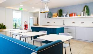 a restaurant with tables and a blue couch at Staybridge Suites - Cardiff, an IHG Hotel in Cardiff