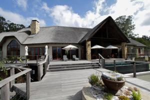 uma casa com uma piscina e um deque de madeira em Tamodi Lodge em Plettenberg Bay